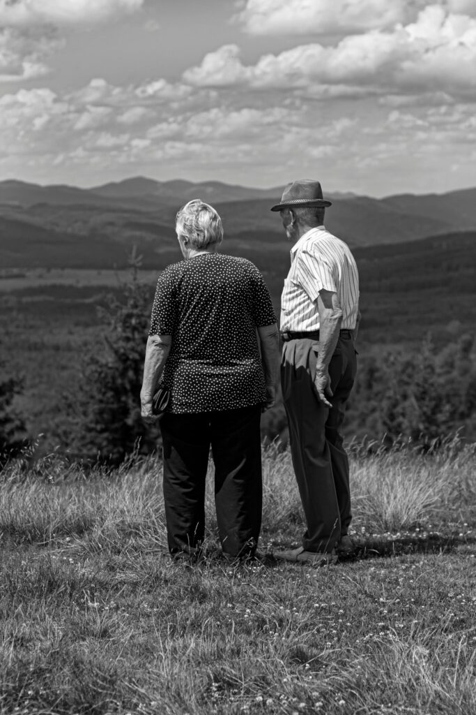 Senior couple standing together, appreciating the panoramic mountain landscape.