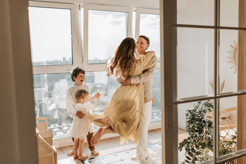 pexels-photo-4609049-4609049 A joyful family embraces in a sunlit modern apartment, celebrating togetherness and love.